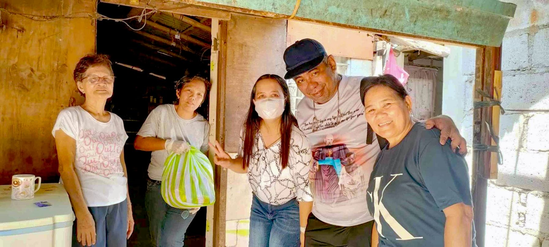 Bro Mario stands with his arms around two parishioners from the Philippines.