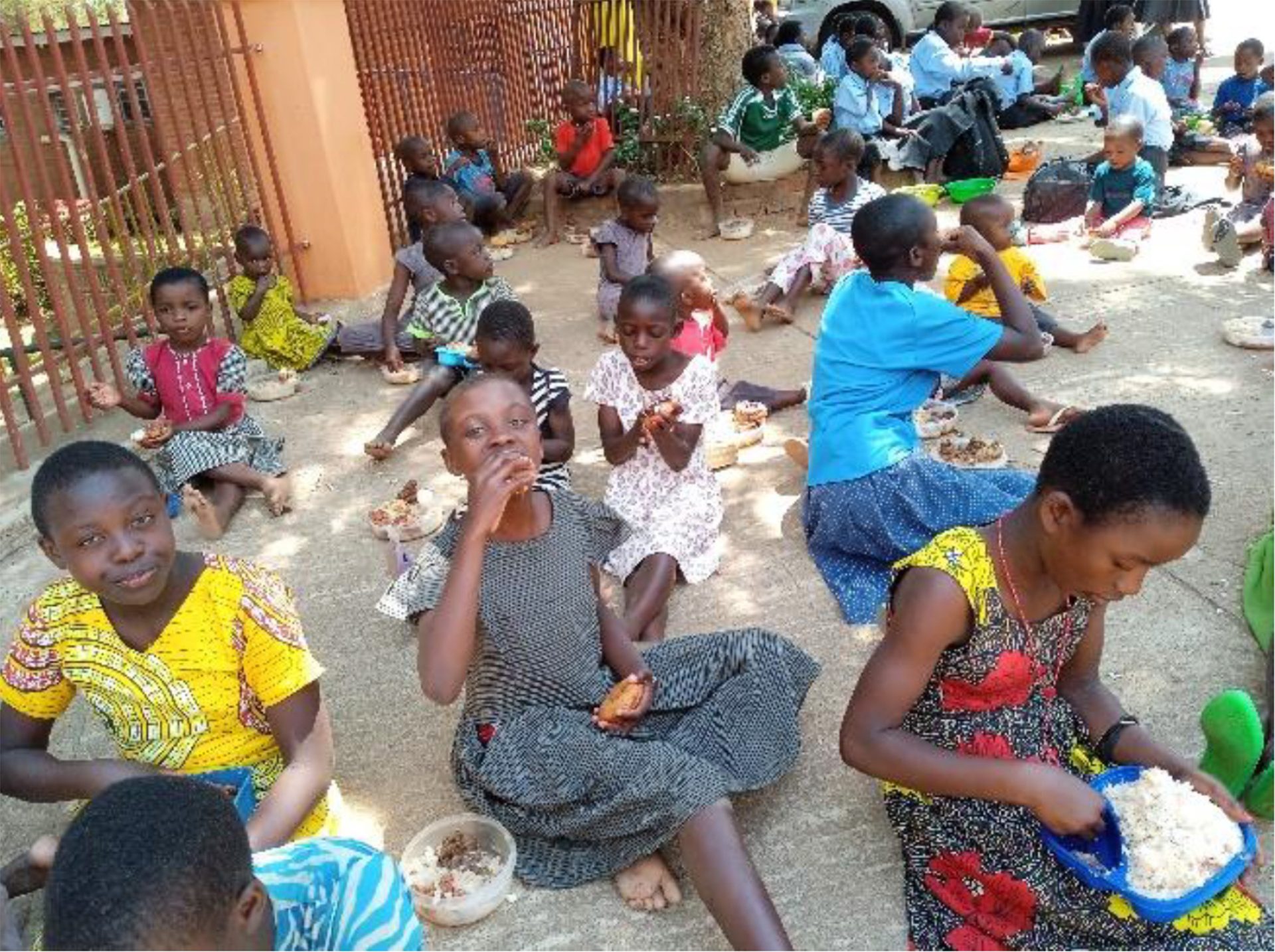Children at a Malawi school sit outside for a meal